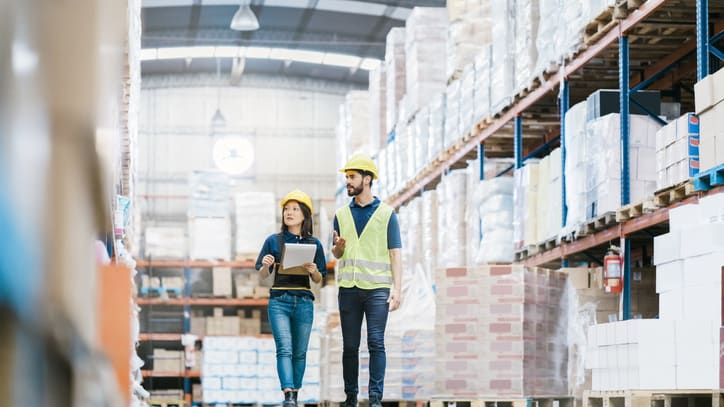 Two warehouse workers walking through a warehouse.