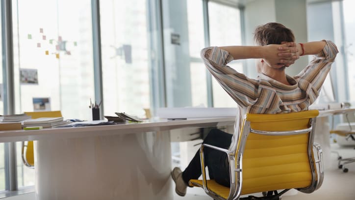 A woman relaxes at her desk in an office.