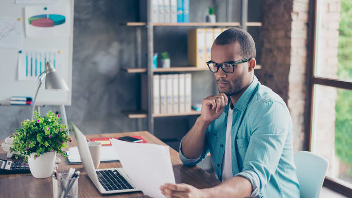 A man sitting at a desk with a laptop and papers.