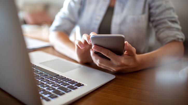 A woman using a cell phone while sitting at a desk.