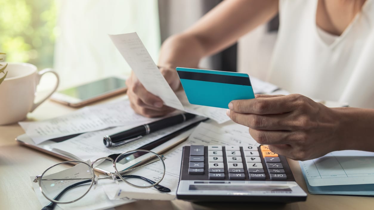 A person holding a credit card and a paper.