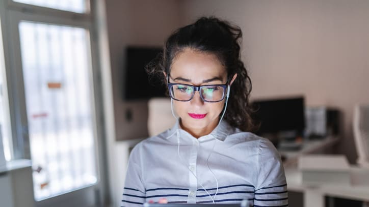 A woman wearing glasses is using a tablet computer.