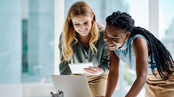 Two women looking at a laptop in an office.