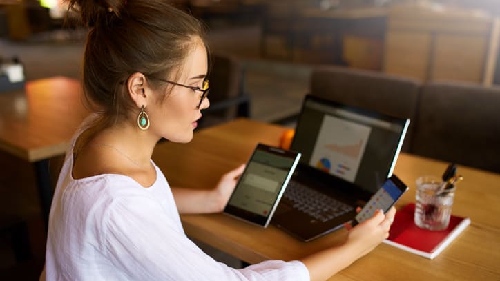 A woman sitting at a table with a laptop and cell phone.