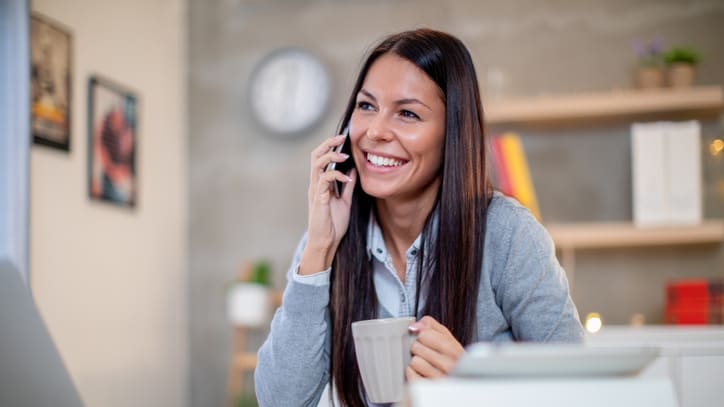 A woman is talking on the phone while sitting at a desk.