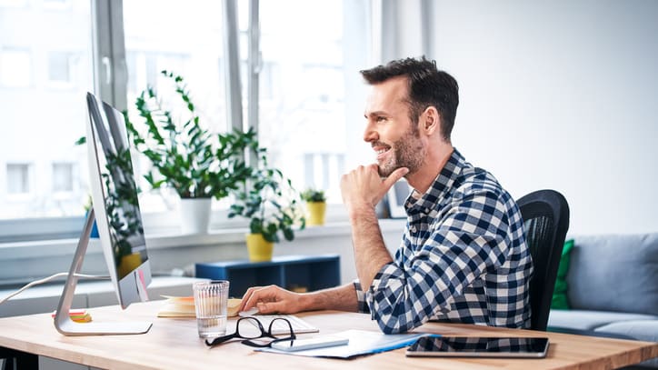 A man sitting at a desk looking at his computer.