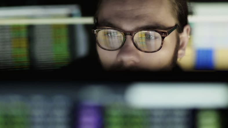 A man in glasses is looking at a computer screen.