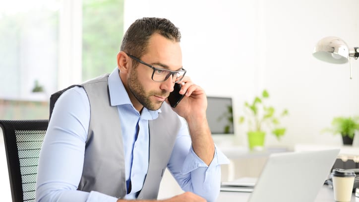 A businessman talking on the phone while sitting at his desk.