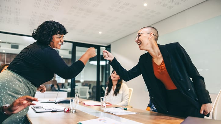 Two business women shaking hands in a meeting room.