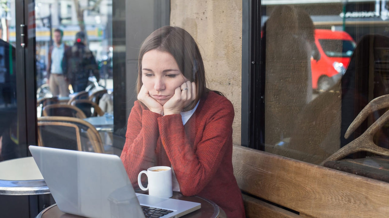 A woman sitting at a table with a laptop in front of her.