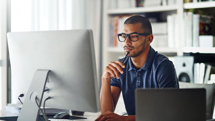 A man sitting in front of a computer looking at the screen.