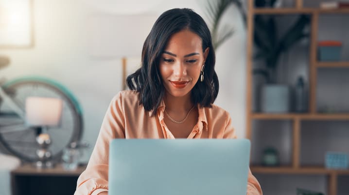 A woman is working on her laptop at home.