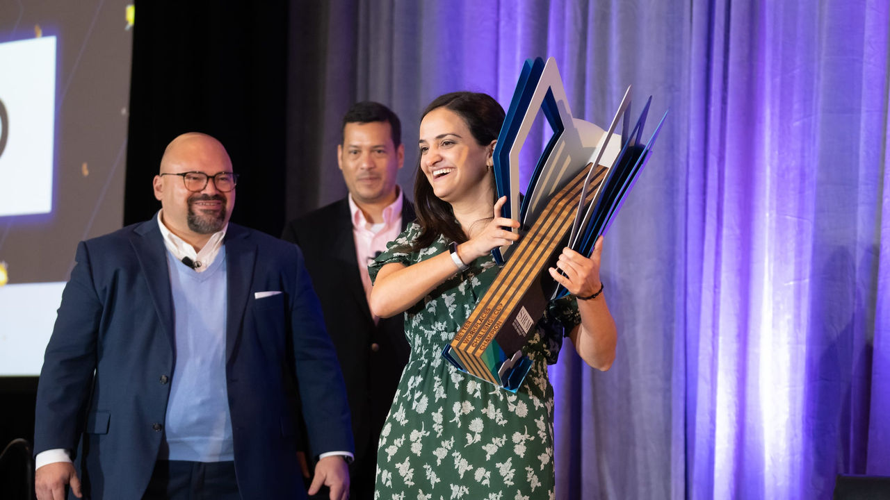 A woman is holding a trophy while standing next to a man.