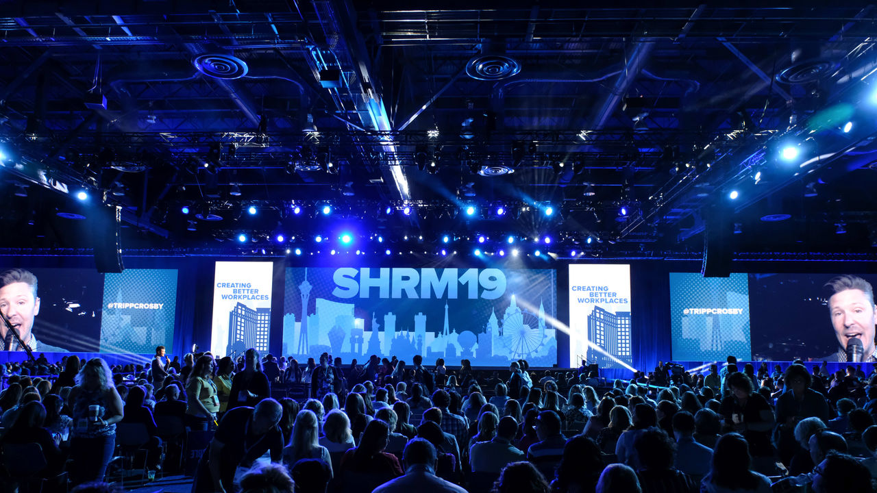 A crowd of people watching a stage at a conference.