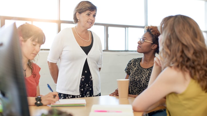 A group of women sitting around a table in an office.