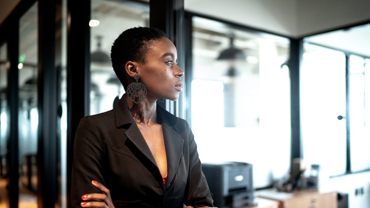 A businesswoman standing in an office with her arms crossed.