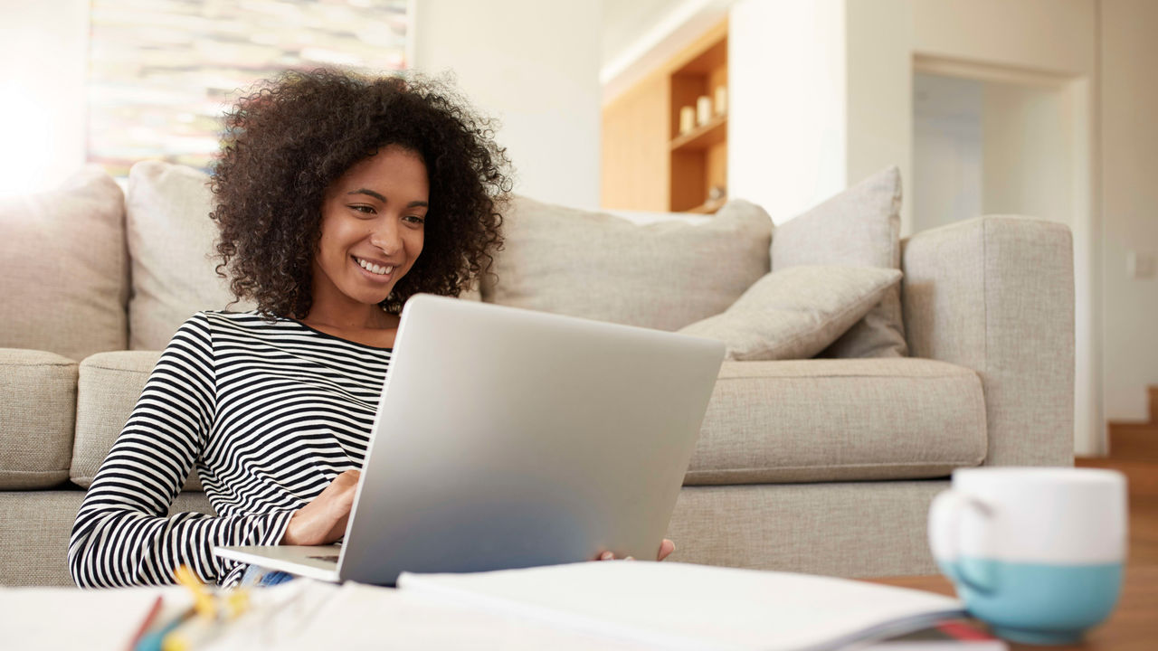 A young woman is sitting on a couch and using a laptop.