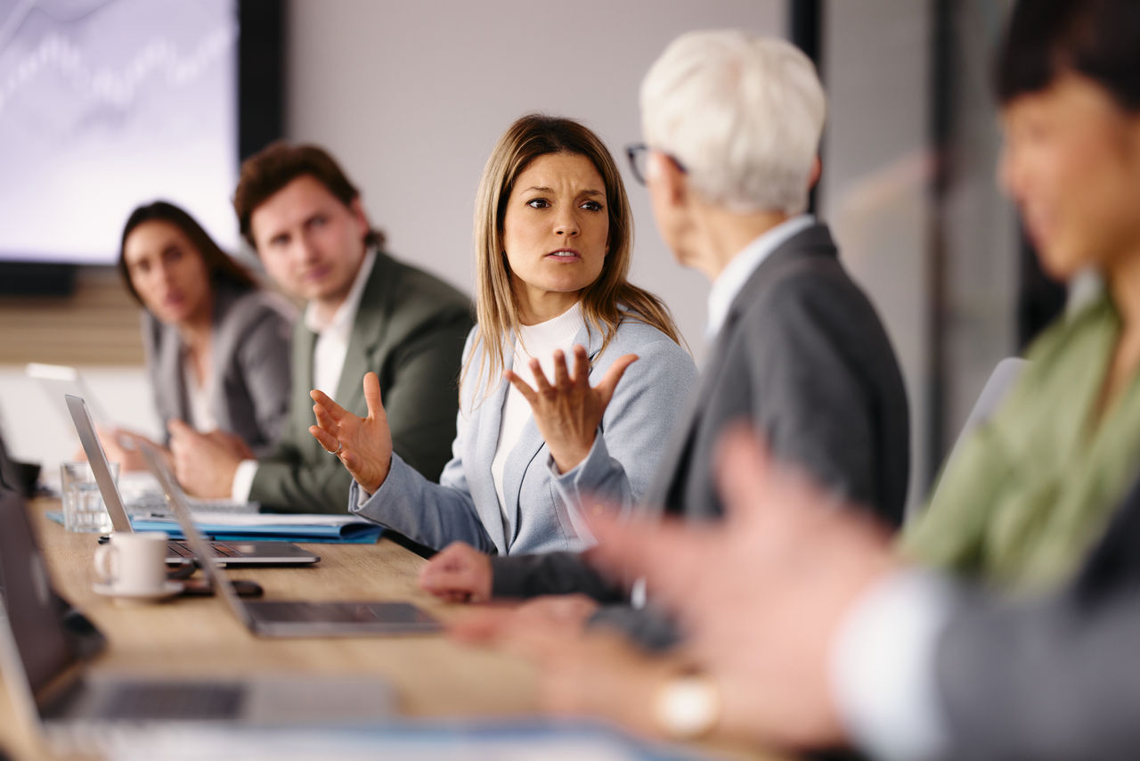 Displeased female entrepreneur arguing with her colleague while working on a meeting in the office.