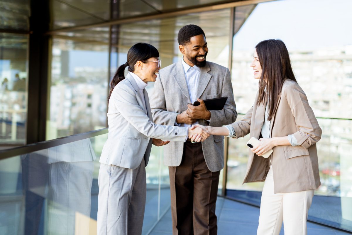 businesswoman smiling while shaking hands with businesswoman