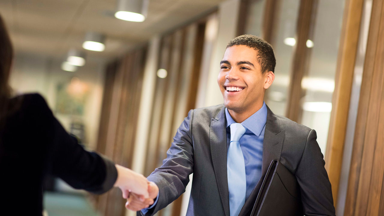 A businessman shaking hands with a woman in an office.