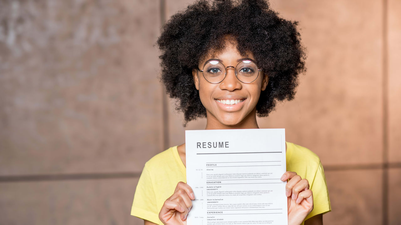 A young woman holding up a resume.