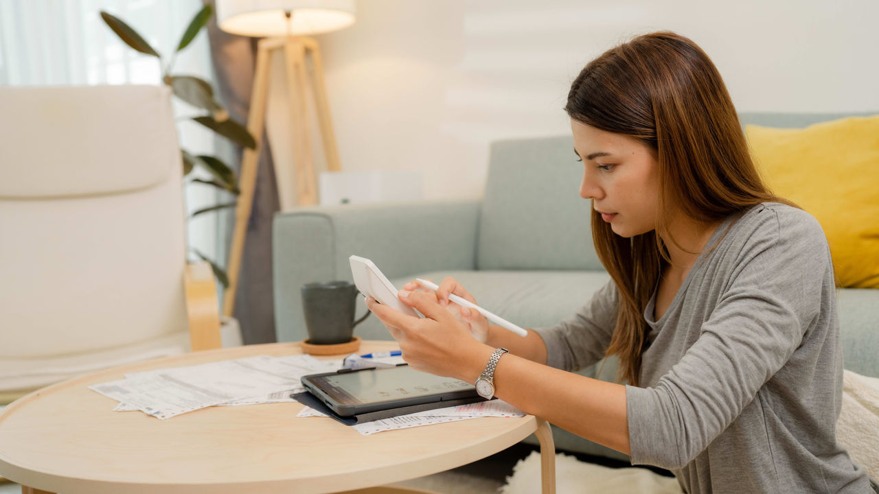 A woman is sitting on a couch and using a cell phone.