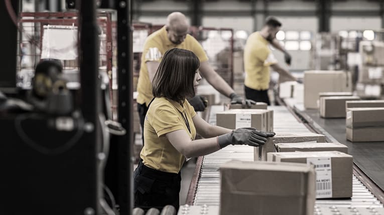 A group of people working on a conveyor belt in a warehouse.