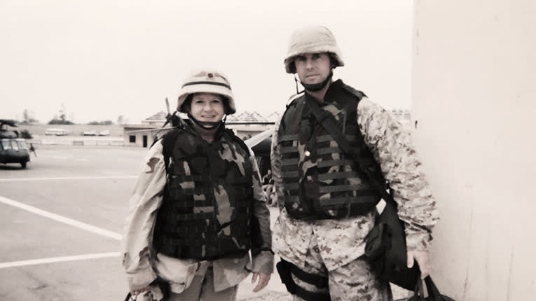 Two marines standing next to each other in a parking lot.