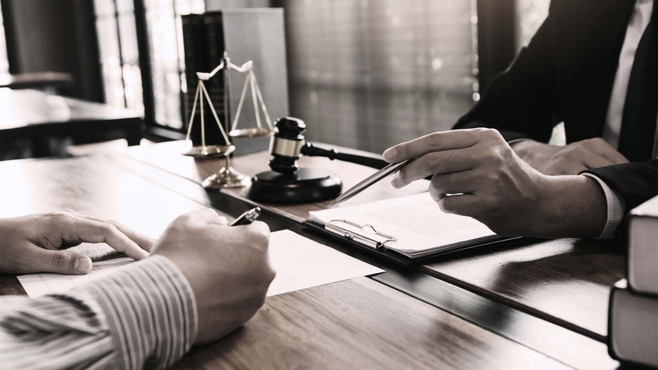 A lawyer signing a document at a desk.