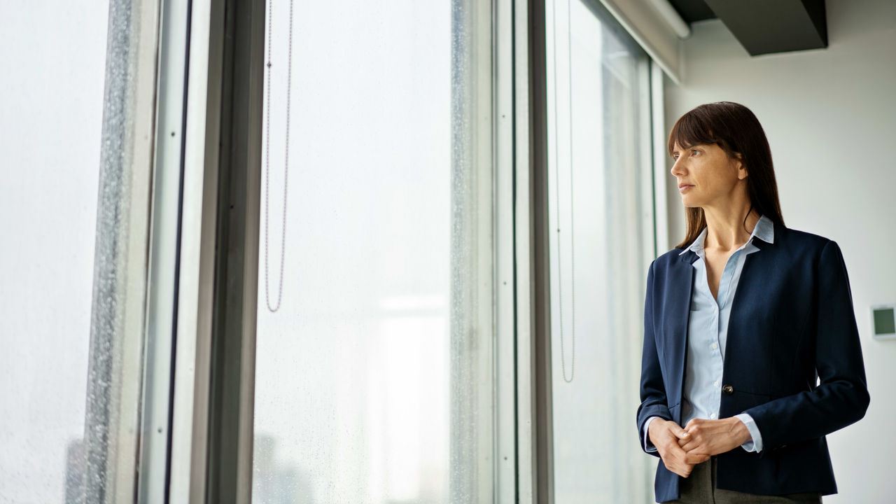 A business woman standing in front of a window.