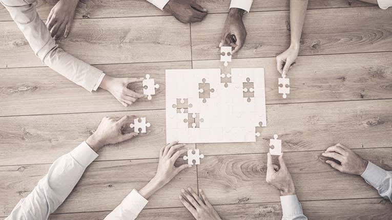 A group of business people holding a puzzle piece.
