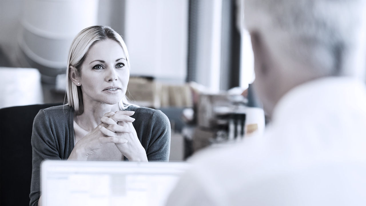 A woman talking to a man in an office.