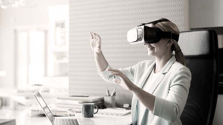 A woman wearing a virtual reality headset in front of a laptop.