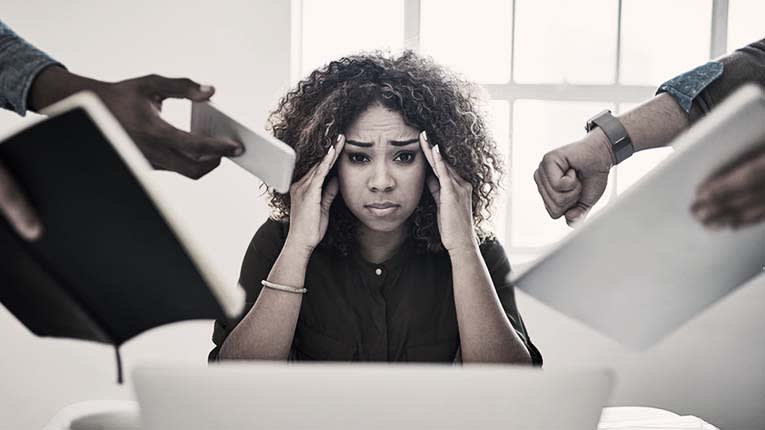 A woman is holding her head in front of a group of people.