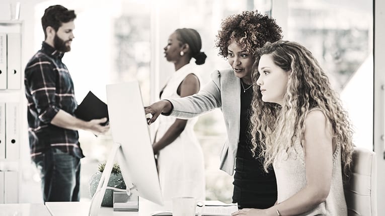 A group of people in an office looking at a computer.