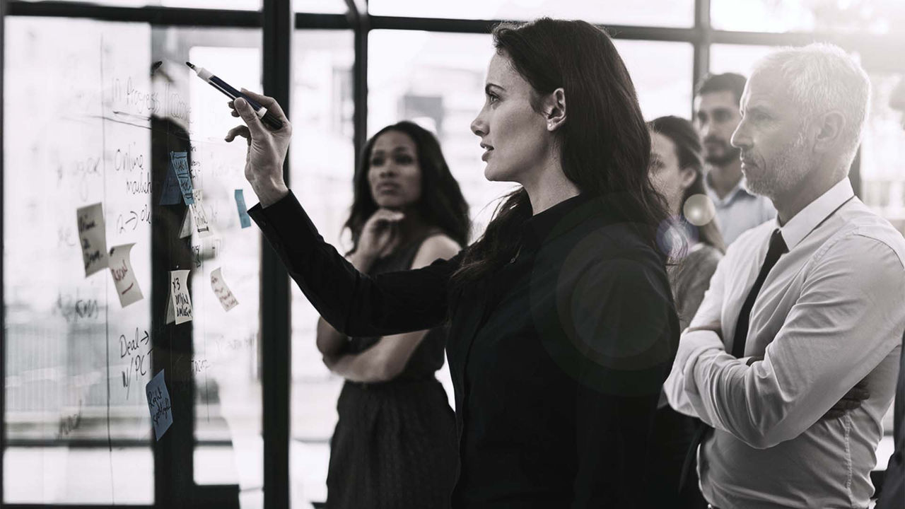 A group of business people standing in front of a whiteboard.