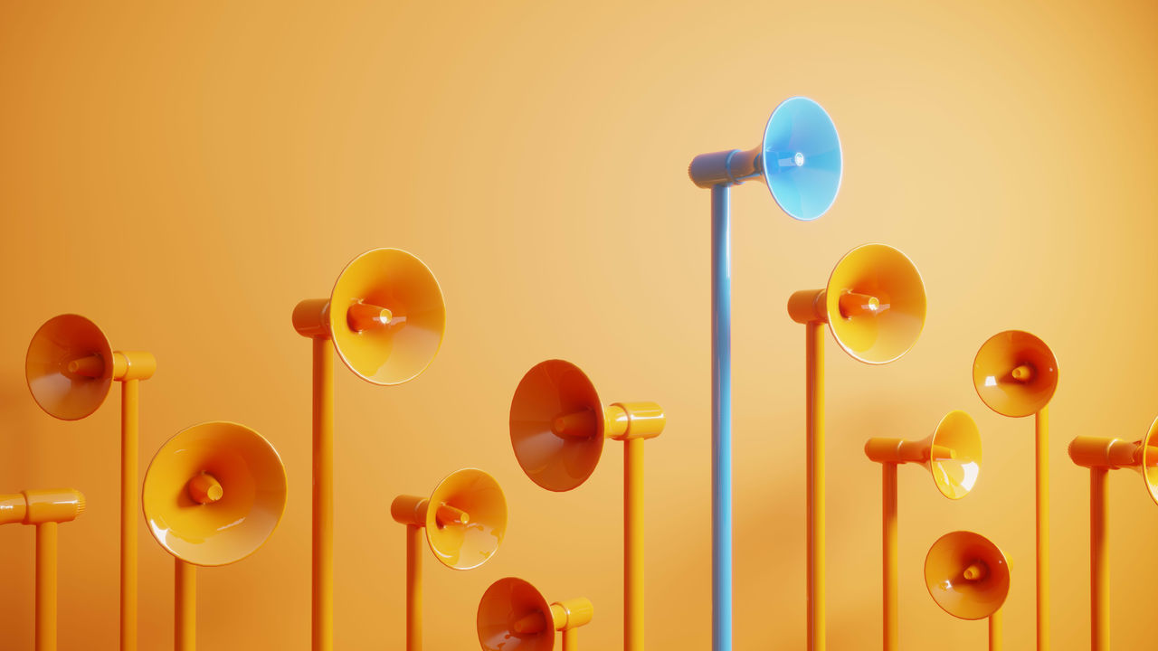 A group of orange and blue speakers on an orange background.