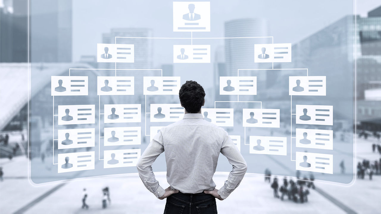 A businessman looking at a tree with people on it.