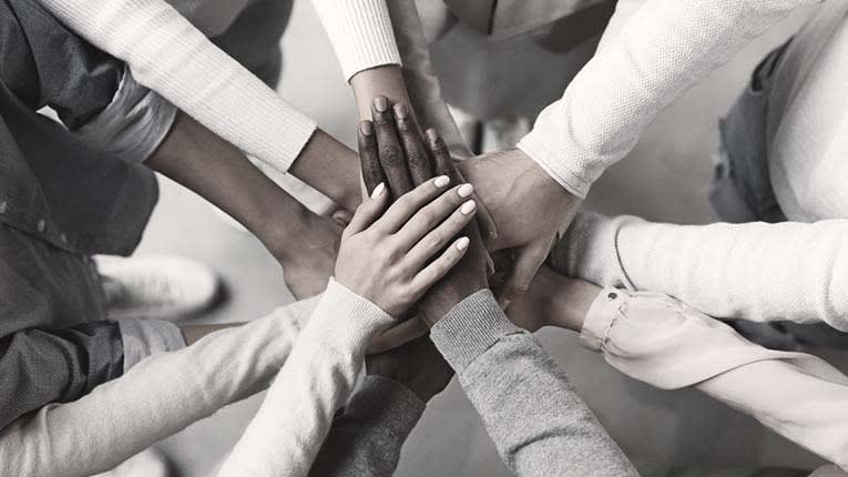 A group of people putting their hands together in a circle.