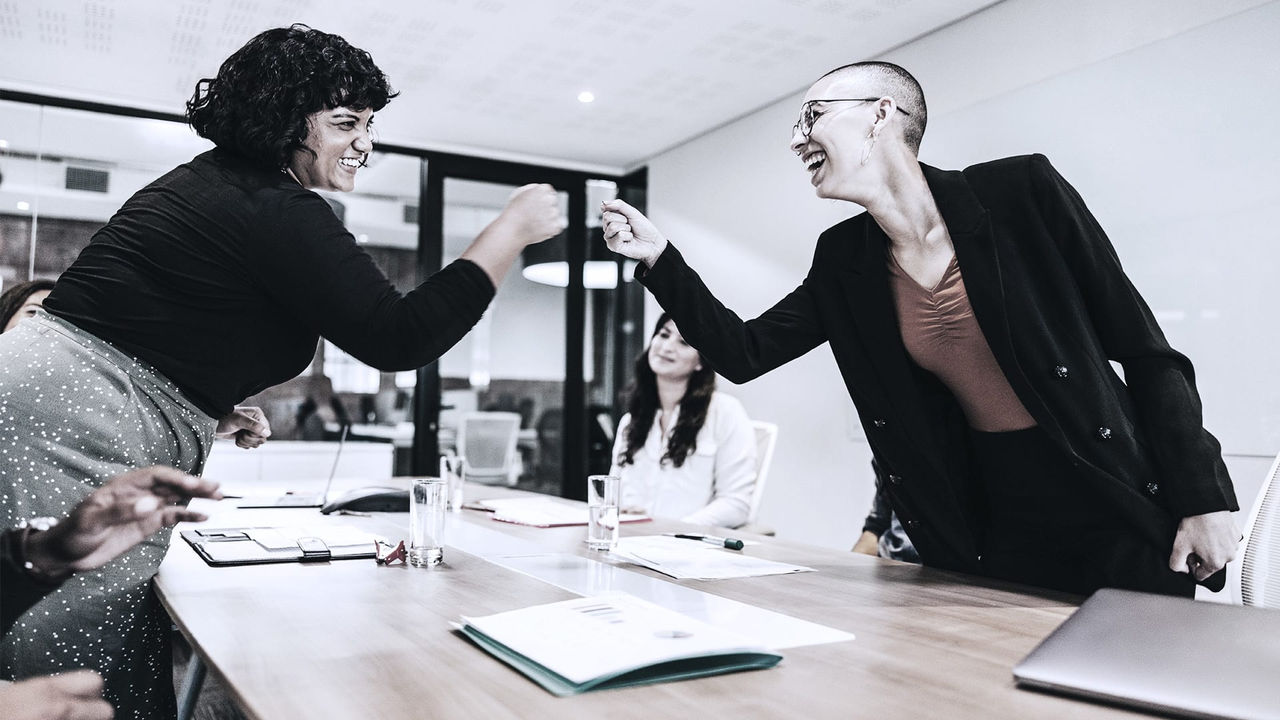 Two women shaking hands in a meeting room.