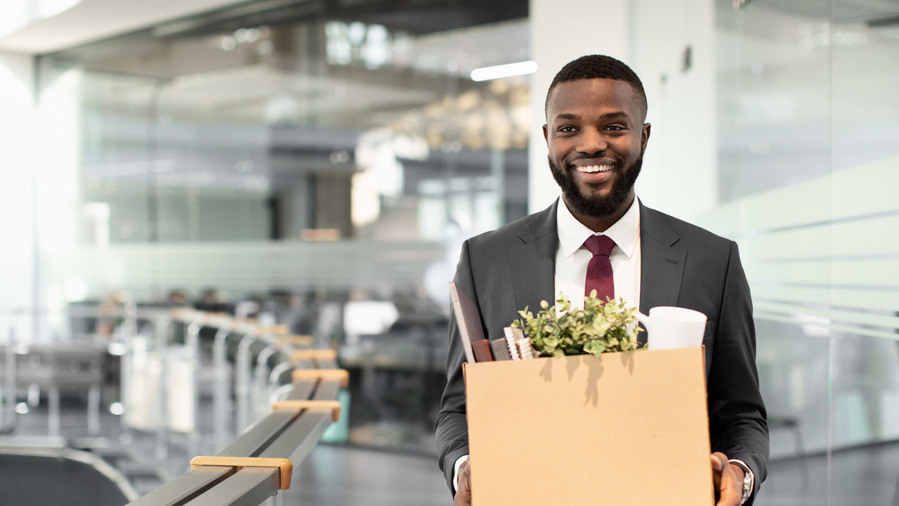 A businessman holding a cardboard box in an office.