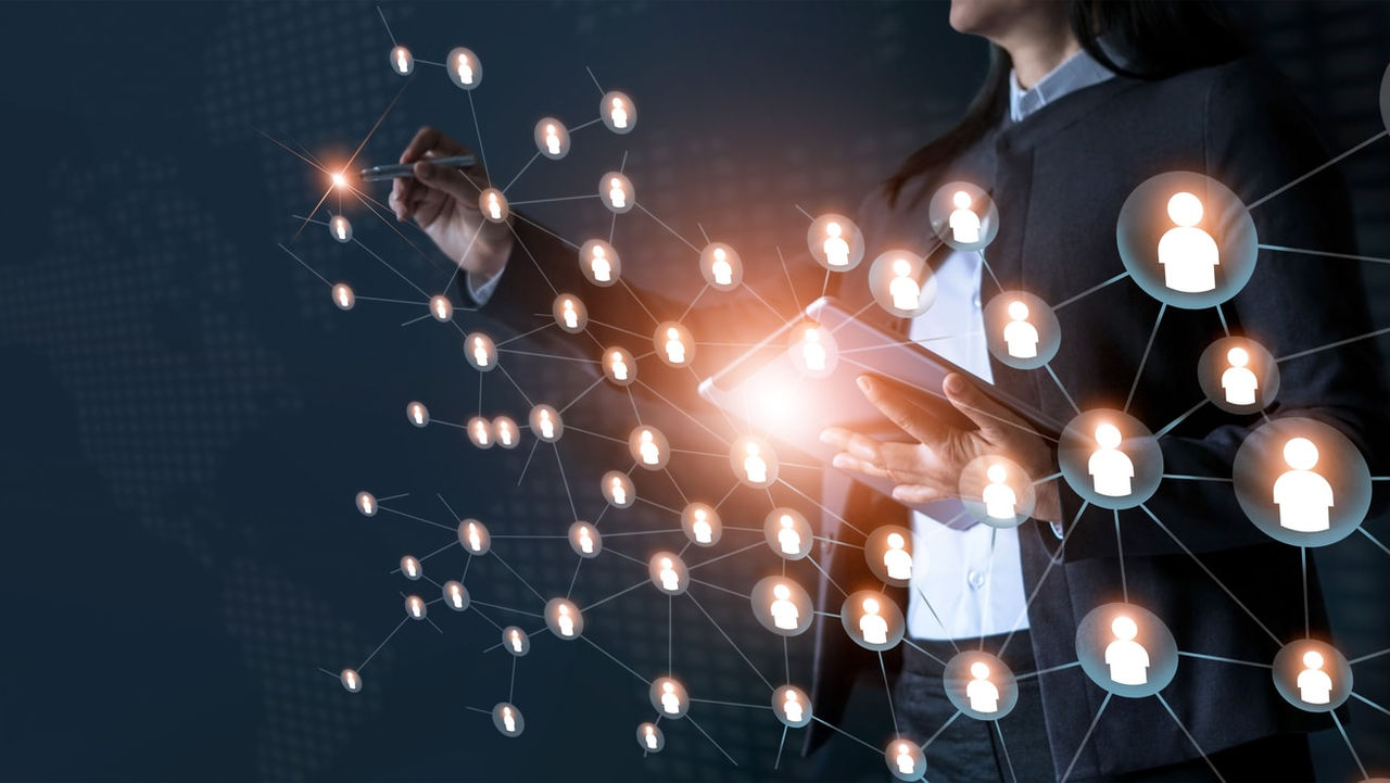 A business woman holding a phone with a network of people connected to it.