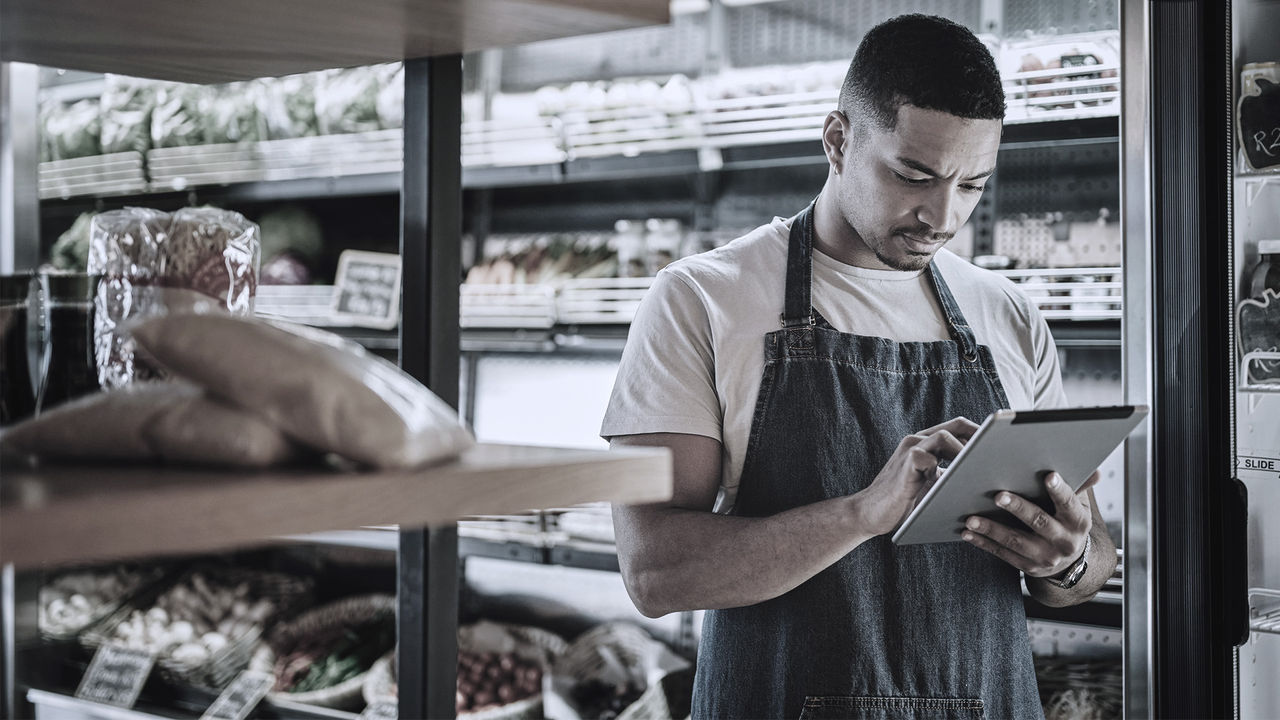 A grocery worker entering info in his ipad near grocery shelves