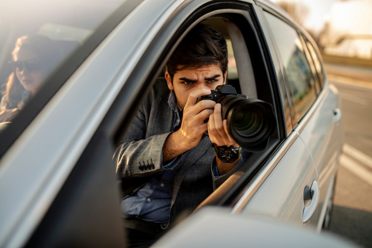 Detective taking picture with camera from car 