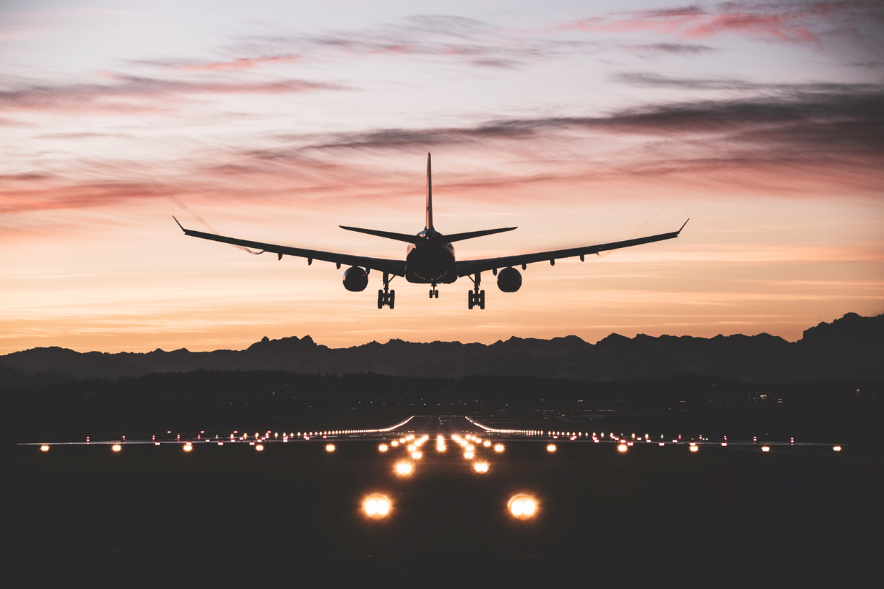 An airplane moments from touching down on the runway at sunrise.