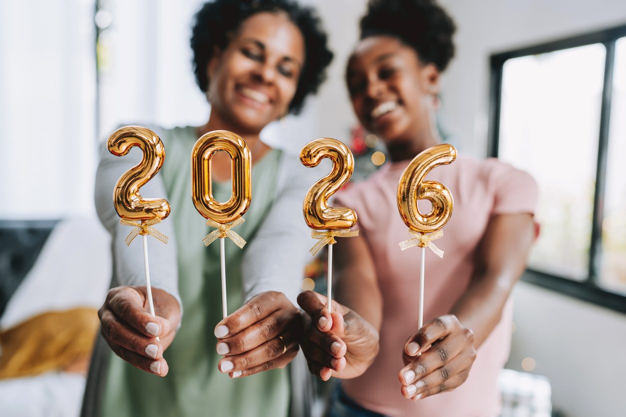 Two women holding up balloons spelling 2026
