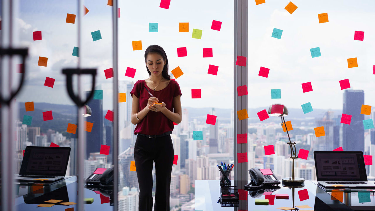 A woman standing in front of a window with sticky notes.