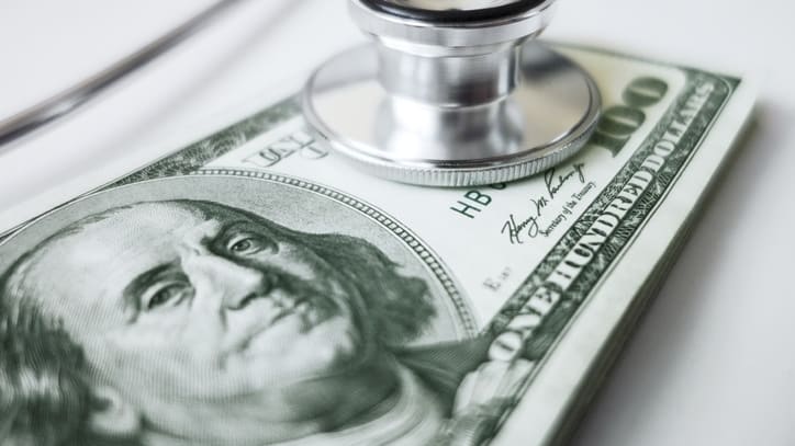 A stethoscope sits on top of a dollar bill.