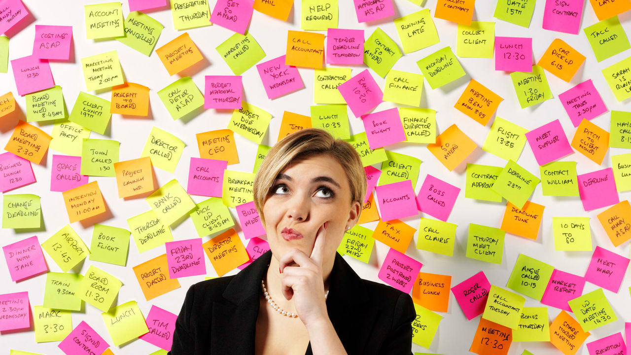 A business woman standing in front of a wall of sticky notes.