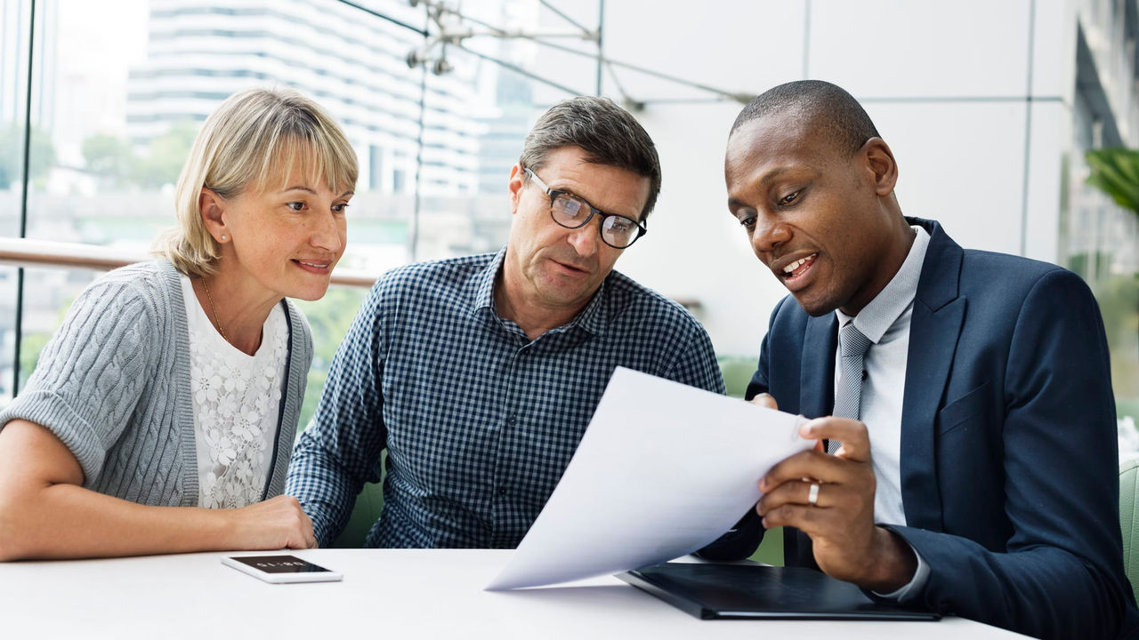 Three business people looking at a piece of paper in an office.